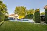Expansive green lawn with a swimming pool, surrounding patio, and a pool house