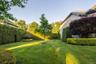 Expansive backyard featuring a lush lawn, mature trees, and meticulously maintained hedges