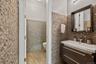 Modern bathroom featuring a dark wood-finish floating vanity with an integrated white sink, a framed mirror, and a wall-mounted faucet