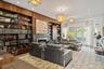 Wood-paneled library featuring extensive built-in shelving, a gas fireplace with a stone surround, recessed lighting, and elegant pendant light fixtur