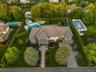 Grand residence featuring a stone and stucco exterior, a multi-car garage, and a lush, manicured landscape