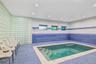 Indoor plunge pool with integrated steps, surrounded by blue mosaic tile flooring and a contrasting blue tile wainscoting