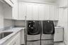 Perfectly placed laundry room with marble countertops & flooring, dual washers and extra-large capacity dryer, built-in cabinetry and full-height clos