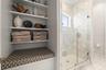 Shared shower and toilet area of the Jack-and-Jill bathroom with marbled shower & floor, built-in shelving and custom upholstered bench with hidden st