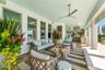 Expansive poolside lanai featuring an inviting entertaining space with automated outdoor stereo, custom planters, bahama shutters, haint blue ceilings