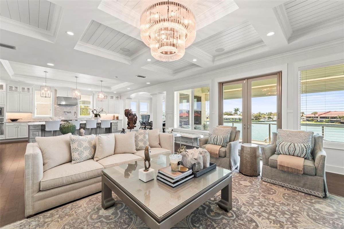 Spacious open-concept great room showcasing a custom surround sound home theatre, crystal chandelier, commissioned artwork, coffered tray ceilings, wa