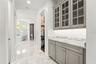 Transition from the primary bedroom into the spa-inspired en-suite bathroom, with marble countertops & floors passing TWO walk-in custom California Cl