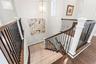 Third story landing with custom staircase leading to the second level with designer lighting and elevator to right
