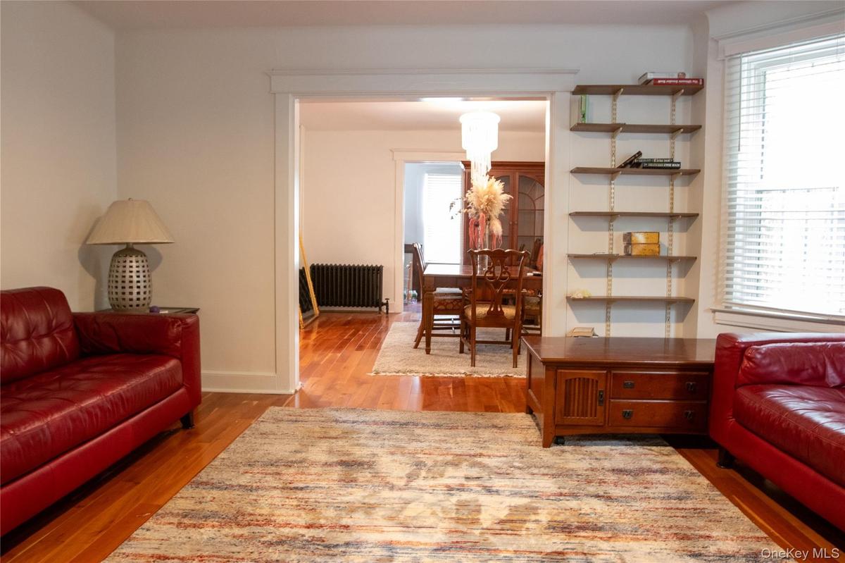 Living area featuring wood-finish flooring, a wide entry to an additional room, and a built-in shelving system