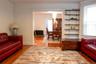 Living area featuring wood-finish flooring, a wide entry to an additional room, and a built-in shelving system