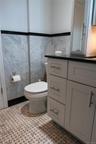 Bathroom featuring a white vanity with brushed nickel hardware, dark countertop, and integrated sink