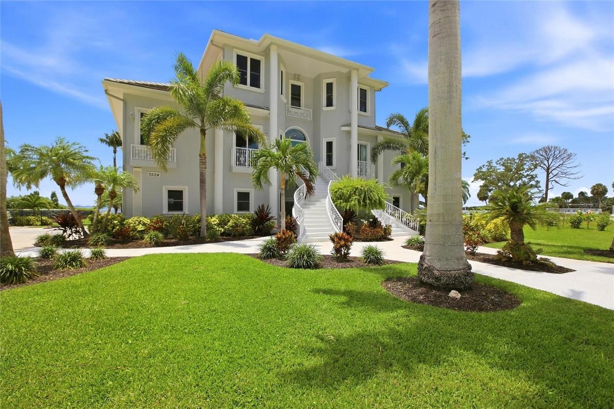 A concrete walkway framed by Royal Palms connects the 2 houses.
