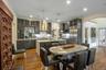 Kitchen with appliances with stainless steel finishes, a kitchen island with sink, wall chimney range hood, pendant lighting, and light hardwood / woo