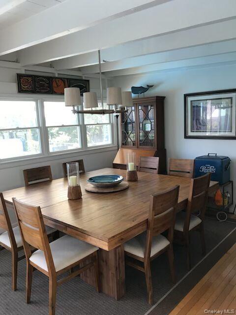 Dining room featuring healthy amount of natural light, wood finished floors, and beamed ceiling
