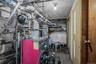 Basement utility area featuring a red boiler unit, exposed piping, and a visible light fixture