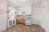 Compact kitchen with patterned floor tiles, white wainscoting, and built-in shelving