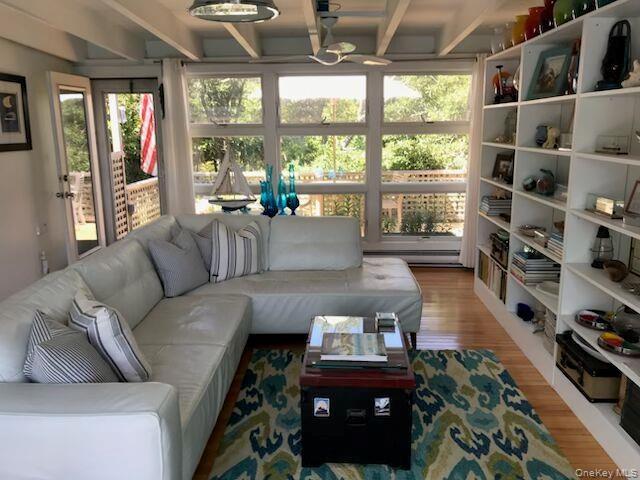 Living area with wood finished floors, a baseboard radiator, and beam ceiling
