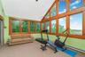 Room featuring extensive natural wood-frame windows, vaulted ceiling, and light green wall finish