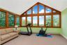 Room featuring expansive windows with wood-finish framing, a vaulted ceiling, and light green wall accents