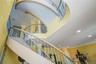 Curving staircase featuring decorative wrought iron balusters, wood-finish handrails, and a grand two-story ceiling