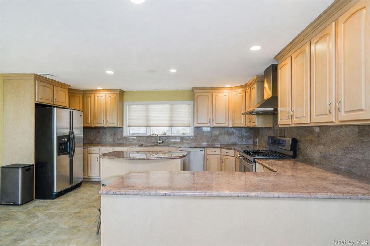 Kitchen featuring light-toned cabinetry, stainless steel appliances, and stone countertops