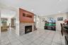 Living room featuring light tile patterned flooring, a glass covered fireplace, recessed lighting, and a baseboard heating unit