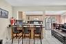 Kitchen featuring tasteful backsplash, light brown cabinets, white appliances, a kitchen bar, and dark countertops