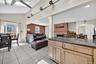 Kitchen with light brown cabinetry, dark stone countertops, light tile patterned floors, open floor plan, and a skylight