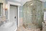 Bathroom featuring ornamental molding, a stall shower, tile walls, and wainscoting