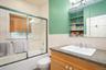 Bathroom featuring tile walls, vanity, combined bath / shower with glass door, and wainscoting