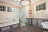 Full bath with wallpapered walls, a wainscoted wall, a garden tub, crown molding, and a marble finish shower
