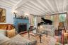 Living room with beamed ceiling, wood finished floors, and a brick fireplace
