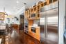 Kitchen featuring wainscoting, built in appliances, crown molding, dark wood-style floors, and light countertops