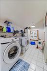 Dedicated utility area featuring white square tile flooring and a built-in shelf