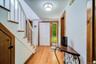 Foyer featuring wood-finish flooring, a white paneled entry door with sidelight, natural wood trim, and a staircase with white risers and wood treads