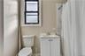 Bathroom featuring a white vanity with a ceramic sink, a chrome faucet, and a two-door cabinet