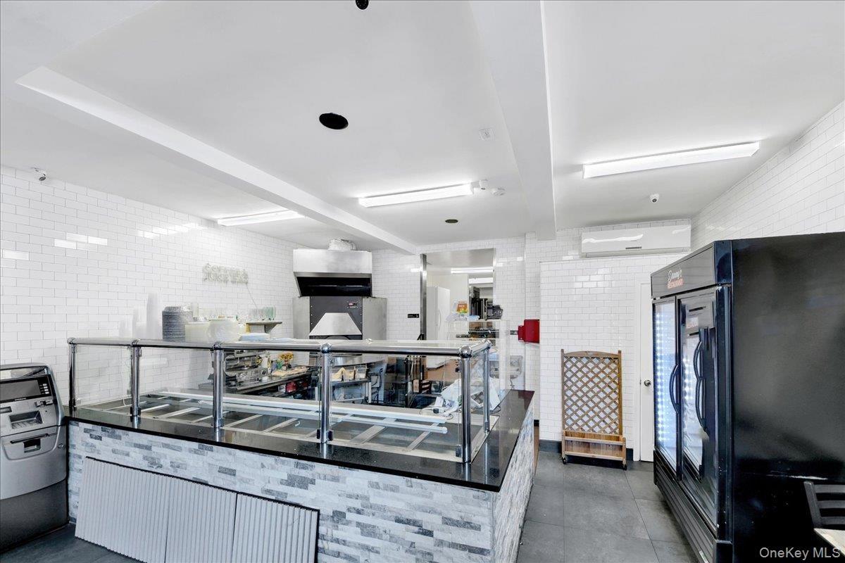 Commercial counter featuring a glass sneeze guard, stone-look base, and dark countertop