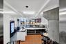 Commercial kitchen and service area featuring a stainless steel display counter, white subway tile wall, recessed lighting, and terracotta-toned floor