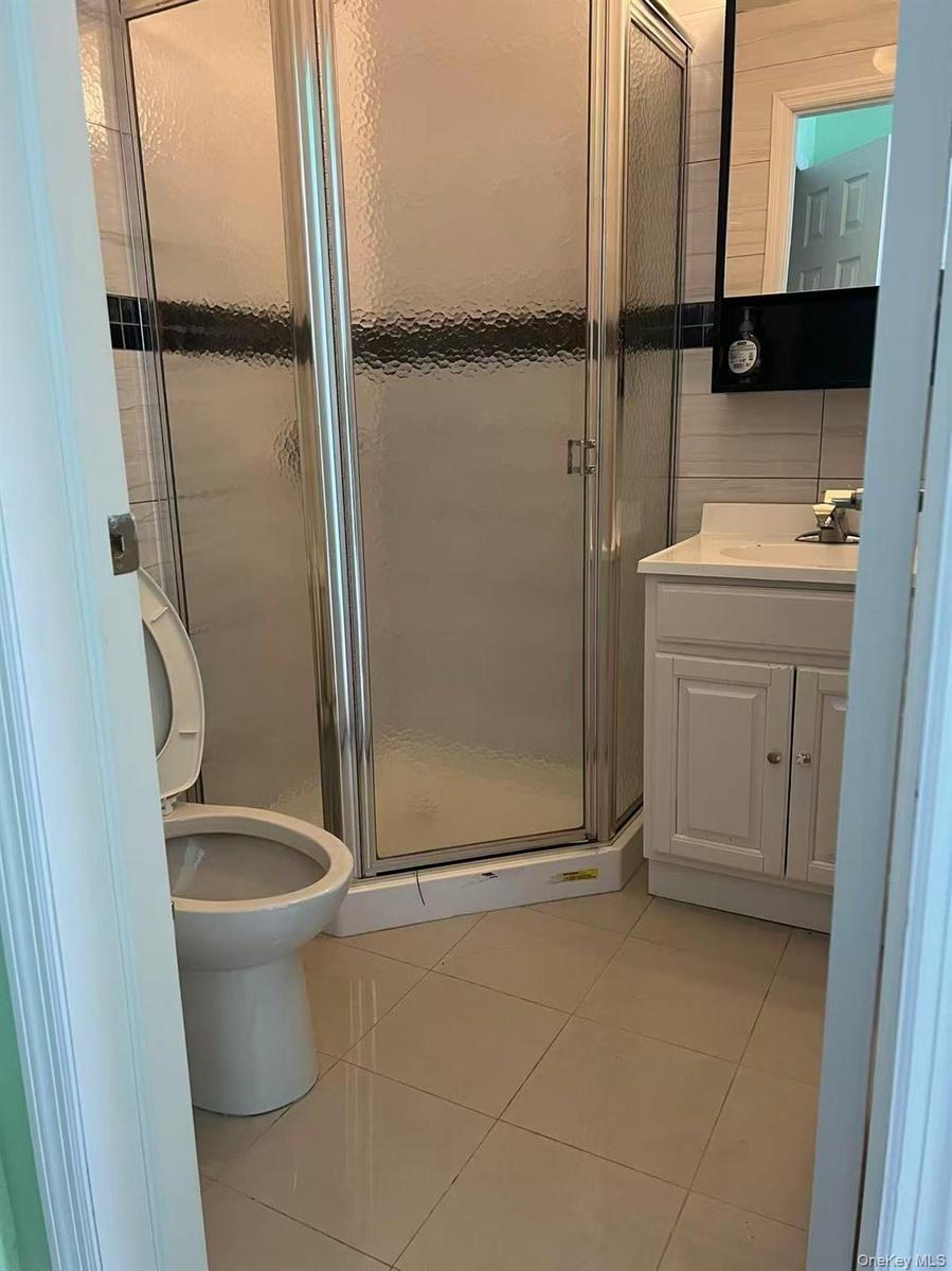 Full bathroom featuring vanity, tile patterned floors, a stall shower, and toilet