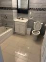 Bathroom featuring tile patterned flooring, toilet, vanity, tile walls, and washtub / shower combination