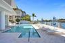 Waterfront Heated Pool along side covered patio, water feature, and built-in BBQ grill