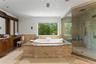 Spa like ensuite primary bathroom with double vanity, large tub and glass enclosed shower