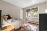 Bedroom featuring wood-finish flooring, neutral wall tones, and a double window with roller shades