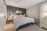 Bedroom featuring a dark accent wall, light neutral wall color, and a window with white blinds