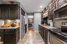 Galley kitchen featuring dark wood cabinetry, stainless steel appliances, light countertops, and wood-finish flooring