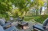 Spacious backyard featuring a stone paver path, mature trees, and string lighting