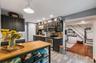 Kitchen featuring dark cabinetry, stainless steel appliances, and a light wood-finish island with open shelving