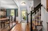 Hardwood flooring throughout entryway and dining area, featuring a staircase with contrasting dark wood handrails and white balusters, and a dining sp