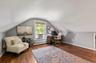 Attic living space featuring wood-finish flooring and a window with blinds