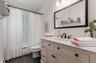 Bathroom featuring a single vanity with a stone countertop, an undermount sink, and a black framed mirror